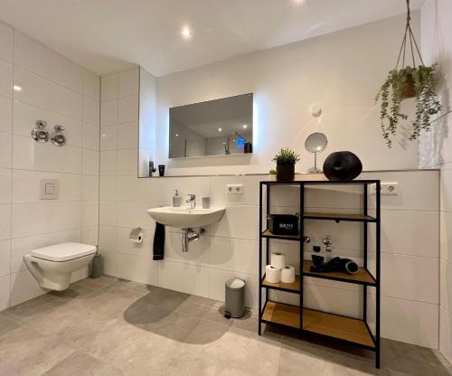 y baño con lavabo, aseo y espejo. en PISO SUPERIOR - Exklusives Apartment an der Promenade mit Rheinsicht & Loggia, en Emmerich