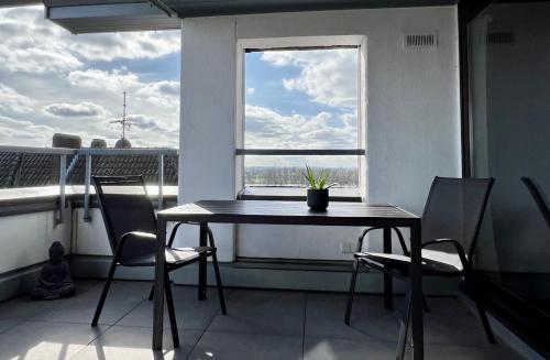 a table and chairs in a room with a window at PISO SUPERIOR - Exklusives Apartment an der Promenade mit Rheinsicht & Loggia in Emmerich