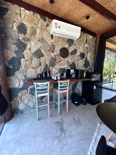 a kitchen with a table and two chairs and a stone wall at Portogalo suíte com SPA in Angra dos Reis