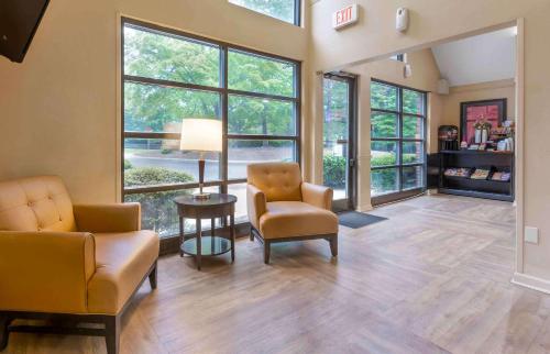 uma sala de estar com 2 cadeiras, uma mesa e janelas em Extended Stay America Suites - Raleigh - Cary - Harrison Ave em Cary