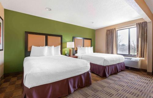 a hotel room with two beds and a window at Suburban Studios Cary - RDU Airport in Cary