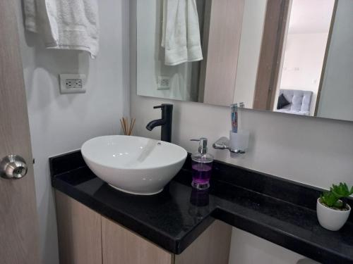 a bathroom with a white sink on a black counter at Espectacular Apartamento en Puerto Azul Club House in Ricaurte