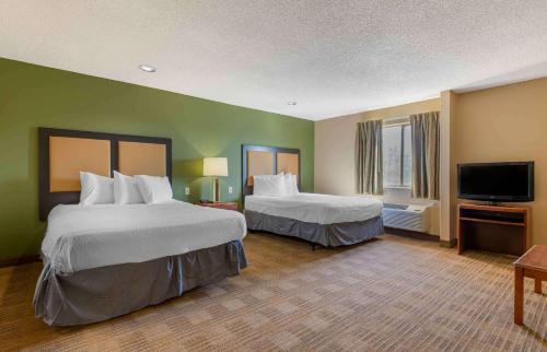 a hotel room with two beds and a flat screen tv at Extended Stay America Suites - Tulsa - Midtown in Tulsa