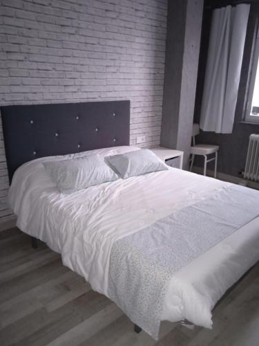 1 dormitorio con 1 cama blanca grande y pared de ladrillo en Apartamento Roma, en Ciudad Rodrigo