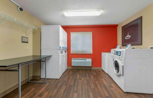 a laundry room with orange walls and a washer and dryer at Extended Stay America Suites - Toledo - Maumee in Maumee