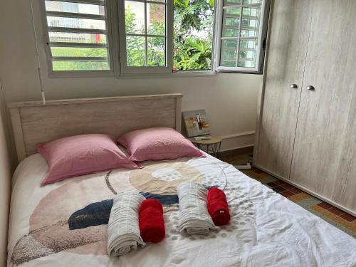 um quarto com uma cama grande e almofadas cor-de-rosa em La Maison Vintage em Petit-Bourg