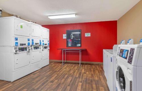 a laundry room with white washing machines and a red wall at Extended Stay America Select Suites - Atlanta - Alpharetta - Northpoint - East in Alpharetta