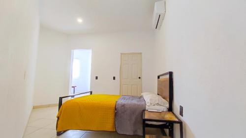 a bedroom with a bed with a yellow blanket at Casa Hansa alojamientos vacacionales in Puerto Vallarta