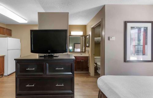 a room with a television on a dresser with a bedroom at Extended Stay America Suites - Raleigh - RTP - 4919 Miami Blvd in Durham