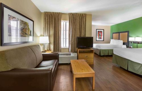 a hotel room with two beds and a couch and a tv at Extended Stay America Suites - Phoenix - Biltmore in Phoenix