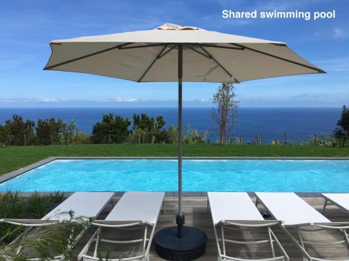 ein Tisch mit Sonnenschirm neben einem Swimmingpool in der Unterkunft Antiga Fábrica de Chá in Nordestinho