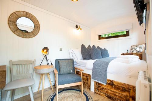 ein Schlafzimmer mit einem Bett, einem Stuhl und einem Spiegel in der Unterkunft The Mar Huts - The Conic Hut in Drymen