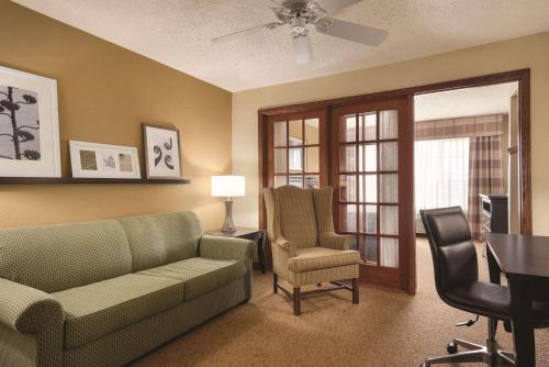 a living room with a couch and a chair and a table at Country Inn & Suites by Radisson, West Bend, WI in West Bend