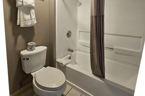 y baño blanco con aseo y ducha. en Rodeway Inn & Suites Thousand Palms - Rancho Mirage, en Thousand Palms