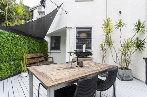 a patio with a wooden table and chairs on a deck at Beachside 2-Bed House with Pool, Courtyard & BBQ in Sunshine Beach