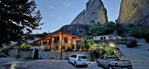 two cars parked in front of a house with a mountain at Voulas Traditional House Meteora 2 in Kalabaka