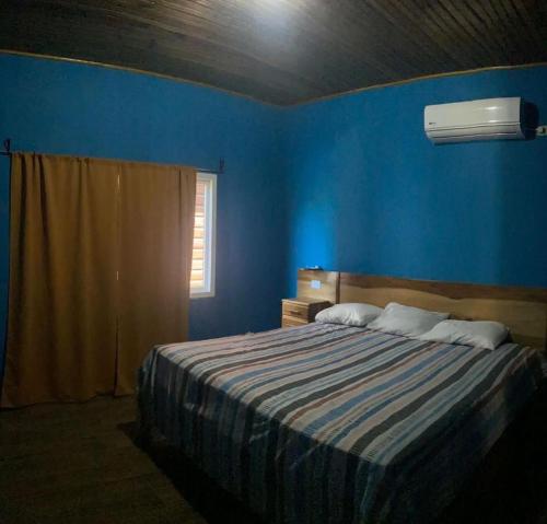 a blue bedroom with a bed and a window at Cabañas Laguna Negra in Tela