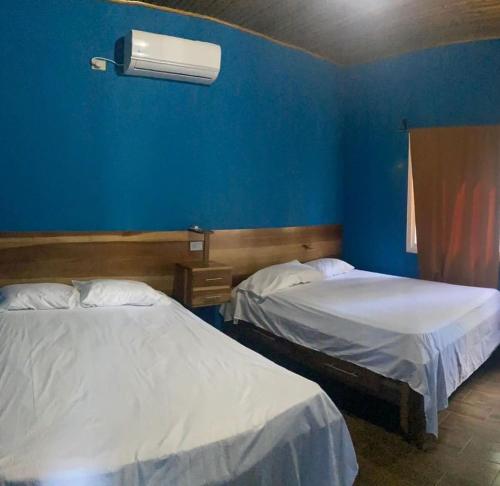 2 camas en una habitación con una pared azul en Cabañas Laguna Negra en Tela
