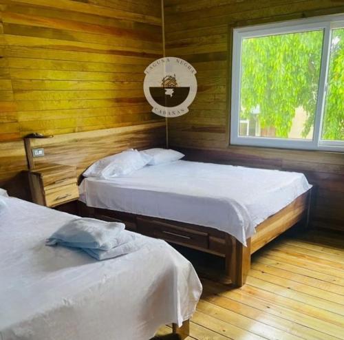 1 dormitorio con 2 camas y ventana en Cabañas Laguna Negra, en Tela