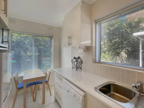 cocina con fregadero, mesa y ventana en Ground floor one bedroom apartment in Elsternwick, en Melbourne