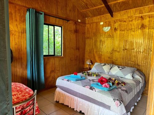 een slaapkamer met een bed in een houten kamer bij Cabañas Tangaroa y Hamea in Hanga Roa