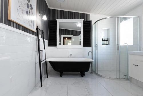 La salle de bains est pourvue d'une baignoire et d'une douche. dans l'établissement Central Elegance: Cottage Gem with Parking, à Launceston