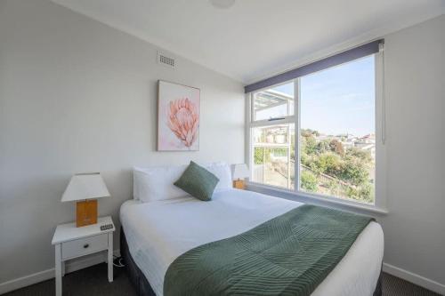 a bedroom with a bed and a large window at Sea You Soon: Views Parking & WiFi in Burnie