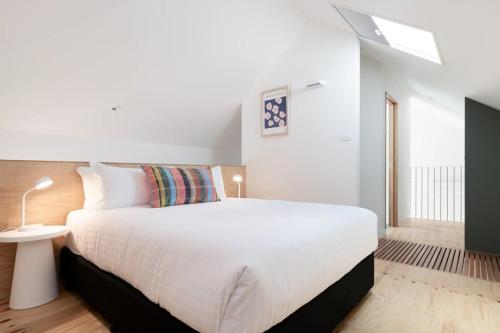 1 dormitorio con 1 cama blanca grande y tragaluz en City Lights & Tiny Delights: Near CBD =& Parking, en Kings Park