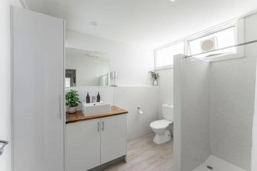 a white bathroom with a sink and a toilet at Cosy Unit With a Sea View in Burnie