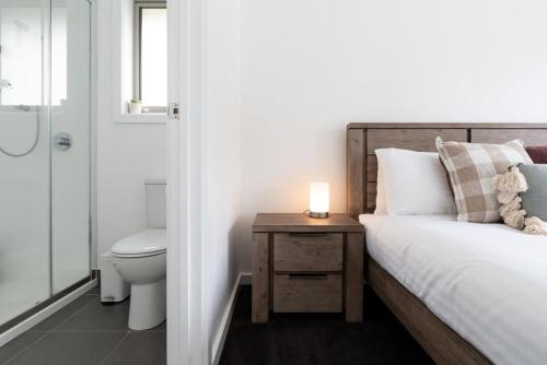a bedroom with a bed and a bathroom with a toilet at Modern Delight: Cosy Home with Parking in Invermay