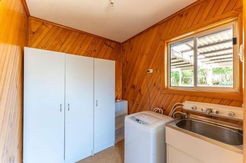 uma lavandaria com uma máquina de lavar roupa e um lavatório em Seabreeze Escape: Your Next Coastal Getaway em Penguin