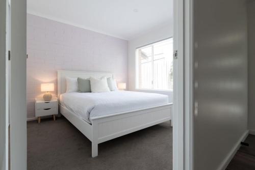 Un dormitorio blanco con una cama blanca y una ventana. en Cosy & Sweet: Near the City WiFi =& Parking, en Kings Park
