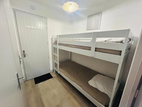 Cette chambre comprend 2 lits superposés et une porte. dans l'établissement BISCAROSSE PLAGE STUDIO TERASSE BARBECUE À 150 m DE LA PLAGE, à Biscarrosse