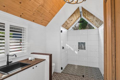a white bathroom with a shower and a sink at Duck Walk Cottage - Boutique Studio Retreat in Burradoo