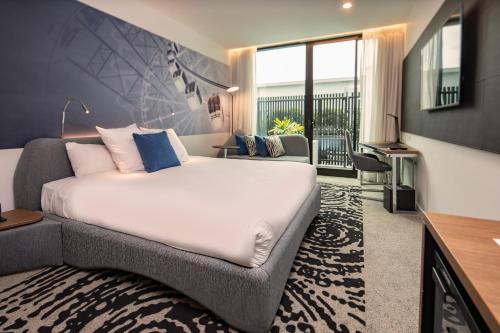 a bedroom with a large bed and a living room at Novotel Brisbane South Bank in Brisbane