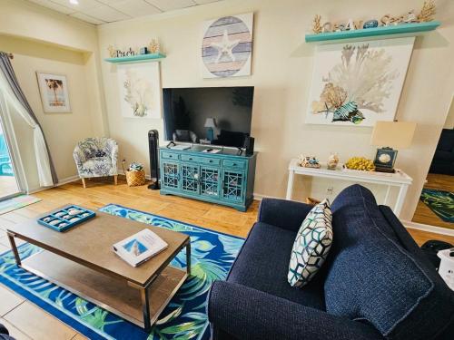 a living room with a blue couch and a table at Pensacola, Oceanfront Paradise With Private Beach in Pensacola Beach