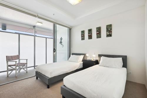 um quarto com duas camas e uma cadeira. em 3-Bed Luxurious Retreat by Brisbane River & CBD em Brisbane