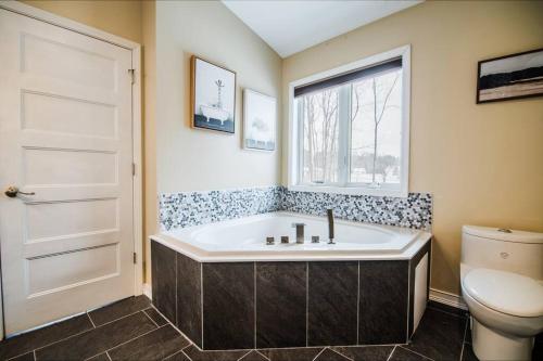 La salle de bains est pourvue d'une baignoire, de toilettes et d'une fenêtre. dans l'établissement Modern Home of Style & Comfort!, à Petoskey