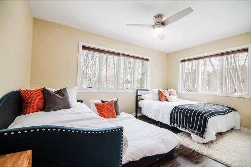 two beds in a room with two windows at Modern Home of Style & Comfort! in Petoskey