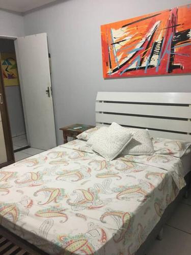 a bed in a bedroom with a painting on the wall at Lugar pra relaxar...Perto de tudo .. in Búzios
