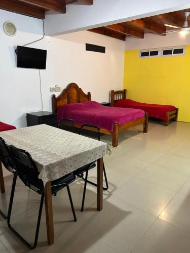 a room with two beds and a table and a tv at Amplio monoambiente in Bella Vista