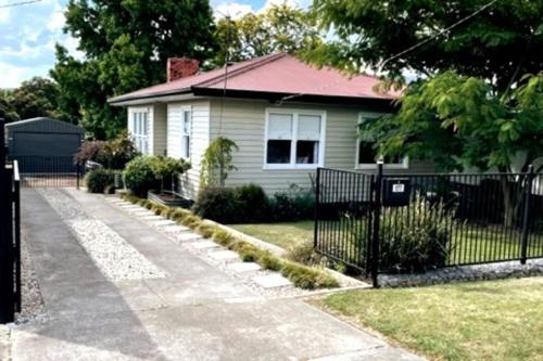a white house with a fence in front of it at Stones on Standish TAHI in Myrtleford