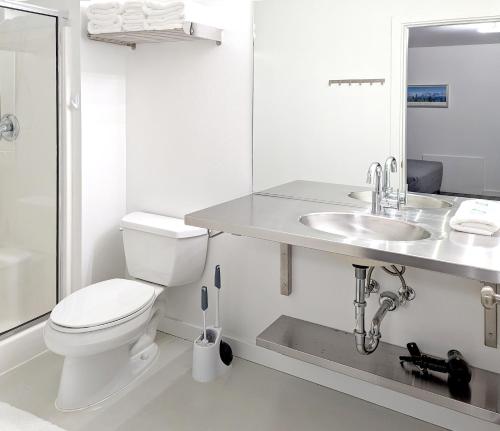 a white bathroom with a toilet and a sink at Snob Hollow Inn Downtown Anchorage in Anchorage