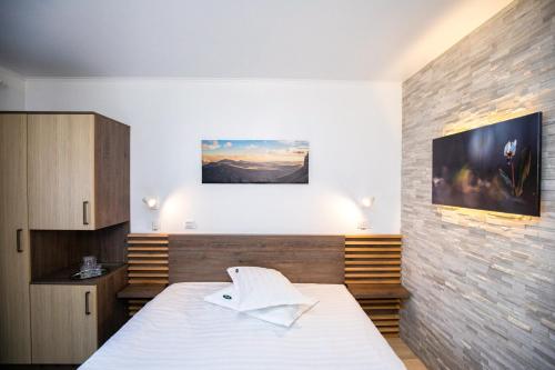 a bedroom with a white bed and a brick wall at Hotel Riviera in Sinaia