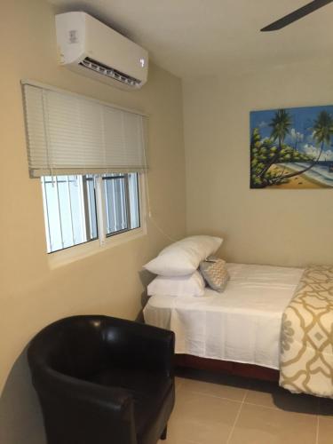 ein Schlafzimmer mit einem Bett und einem Stuhl darin in der Unterkunft Cozy Studios-Private Entrance- HS Internet-AC-Hot Water-Backup Generator-near the Beach in San Felipe de Puerto Plata