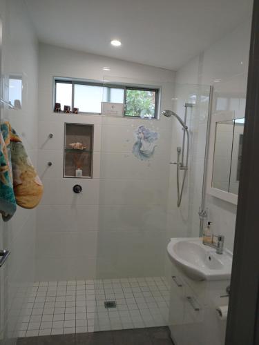 a white bathroom with a shower and a sink at Our Retreat in Forster