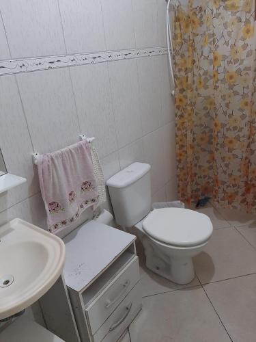 a white bathroom with a toilet and a sink at Confortável quarto em Matinhos in Matinhos