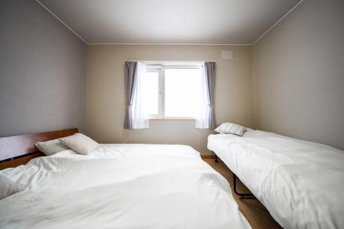two beds in a room with a window at Learch Asahikawa in Asahikawa