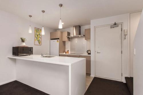a white kitchen with a sink and a refrigerator at Funky Spacious 2Bdrms 2Bthrms Free Covered Park. in Christchurch