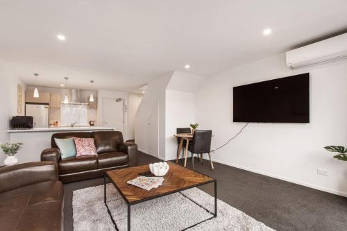 a living room with a couch and a television on a wall at Funky Spacious 2Bdrms 2Bthrms Free Covered Park. in Christchurch